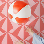 Parasol wallpaper is designed with overlapping shapes of multicolored beach umbrellas. Highly durable, fade resistant, and made in the USA. This wallpaper has a coral print on a pink background and is designed in collaboration with The Aesthetics of Joy.