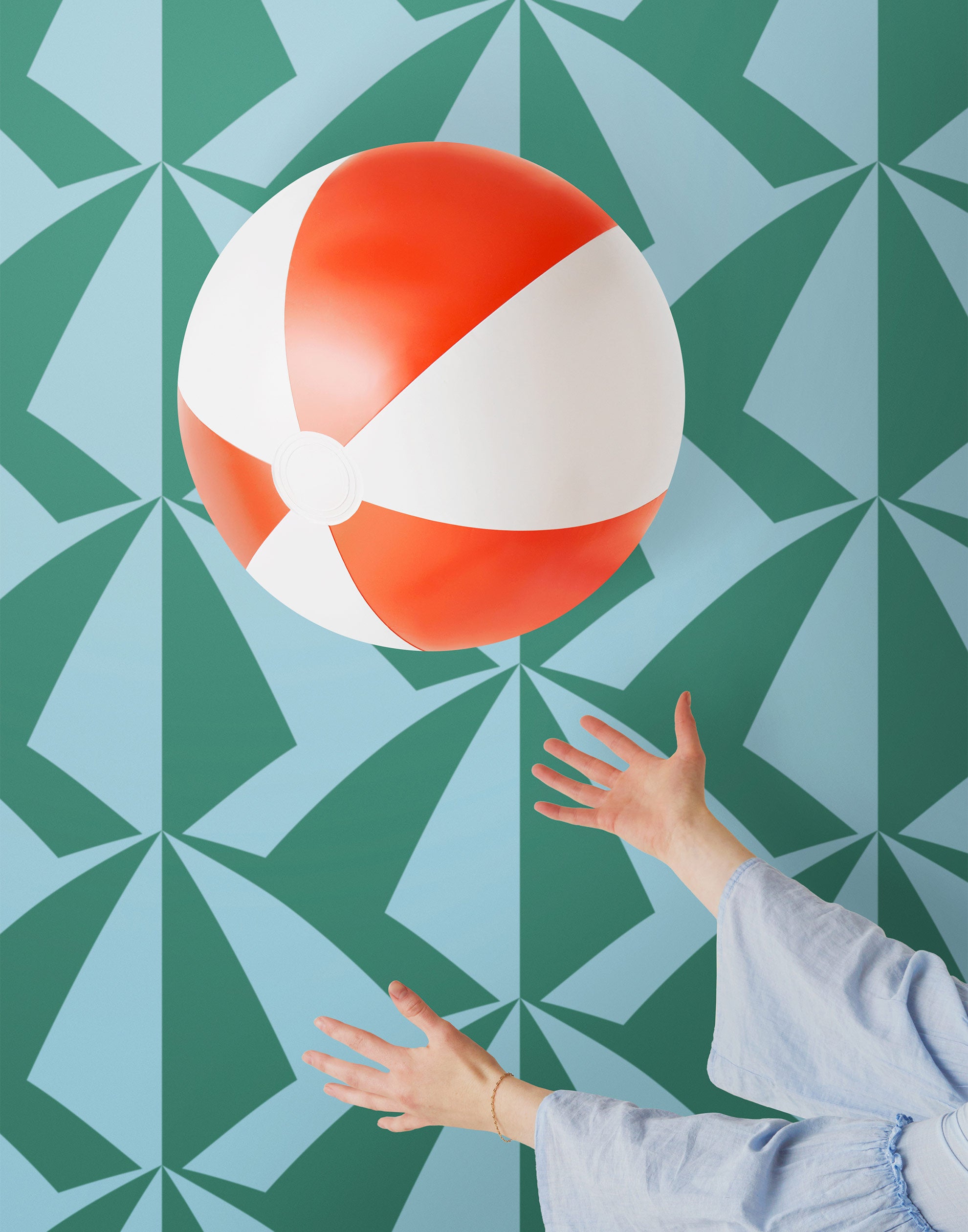 Parasol wallpaper is designed with overlapping shapes of multicolored beach umbrellas. Highly durable, fade resistant, and made in the USA. This wallpaper has a green print on a light blue background and is designed in collaboration with The Aesthetics of Joy.