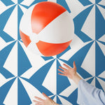 Parasol wallpaper is designed with overlapping shapes of multicolored beach umbrellas. Highly durable, fade resistant, and made in the USA. This wallpaper has a blue print on a white background and is designed in collaboration with The Aesthetics of Joy.