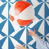 Parasol wallpaper is designed with overlapping shapes of multicolored beach umbrellas. Highly durable, fade resistant, and made in the USA. This wallpaper has a blue print on a white background and is designed in collaboration with The Aesthetics of Joy.