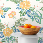 Our Lanai wallpaper is inspired by the rich tradition and exuberant patterns of Hawaiian shirts, with a twist. Highly durable, fade resistant, and made in the USA. This wallpaper features yellow flowers with green and blue leaves on a white background and was created in collaboration with The Aesthetics of Joy.