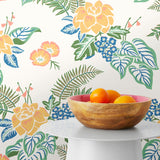 Our Lanai wallpaper is inspired by the rich tradition and exuberant patterns of Hawaiian shirts, with a twist. Highly durable, fade resistant, and made in the USA. This wallpaper features yellow flowers with green and blue leaves on a white background and was created in collaboration with The Aesthetics of Joy.