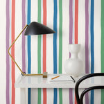 Our Picnic wallpaper was inspired by the wavy stripes of a picnic blanket. Highly durable, fade resistant, and made in the USA. This wallpaper has green, blue, red and purple stripes on a white background and was made in collaboration with The Aesthetics of Joy.
