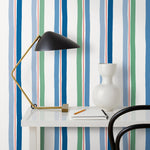 Our Picnic wallpaper was inspired by the wavy stripes of a picnic blanket. Highly durable, fade resistant, and made in the USA. This wallpaper has blue and green stripes on a white background and was made in collaboration with The Aesthetics of Joy.