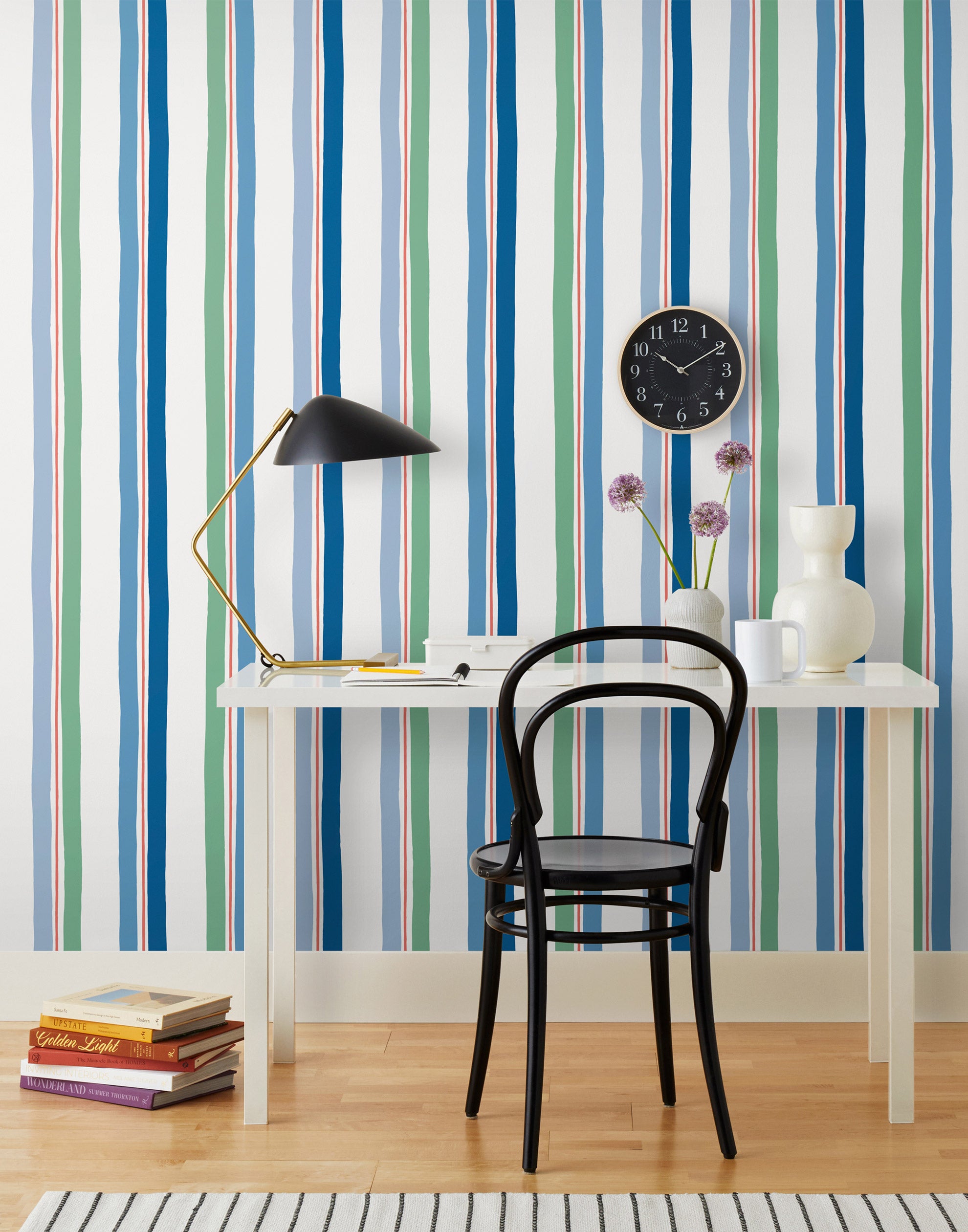 Our Picnic wallpaper was inspired by the wavy stripes of a picnic blanket. Highly durable, fade resistant, and made in the USA. This wallpaper has blue and green stripes on a white background and was made in collaboration with The Aesthetics of Joy.