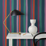 Our Picnic wallpaper was inspired by the wavy stripes of a picnic blanket. Highly durable, fade resistant, and made in the USA. This wallpaper has red, purple, lilac and green stripes on a navy blue background and was made in collaboration with The Aesthetics of Joy.