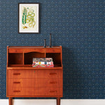 Zinnia (Indigo) Wallpaper mixes a geometric layout with the soft details of the zinnia flower. Black, gray and blue illustration on a navy blue ground.