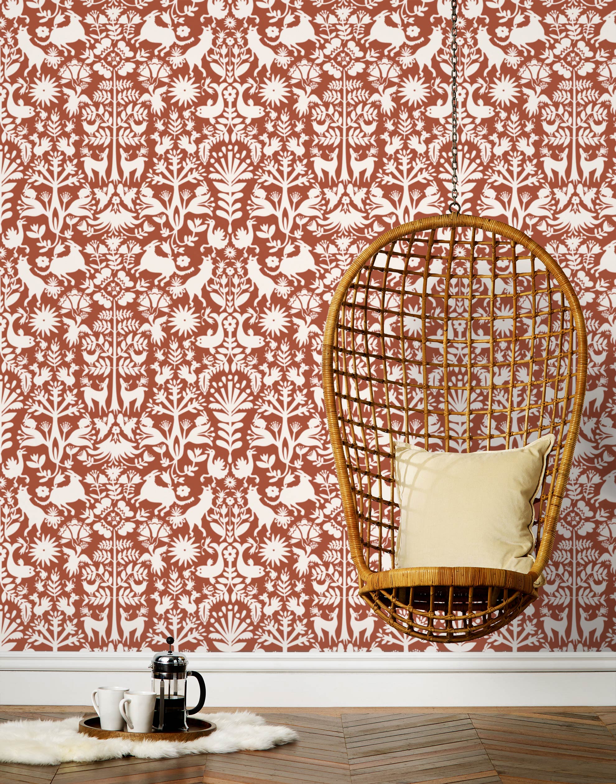 Folklore (Terracotta) features white animals and flowers in a mirroring pattern on a terracotta red backgroud designed by Emily Isabella for Hygge & West