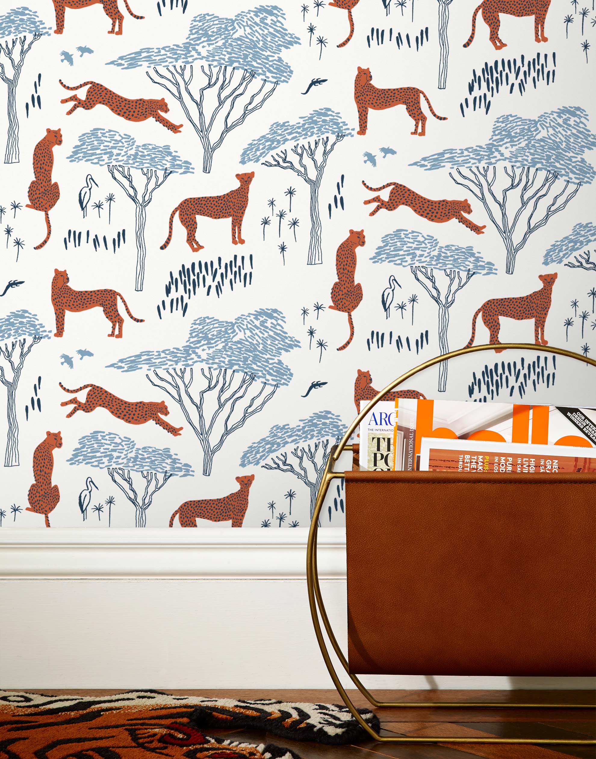 Our Serengeti wallpaper features orange cheetahs and navy birds scattered among blue acacia trees on a white background, reflecting the powerful beauty of the vast plains. Designed by Julia Rothman and made in the USA.