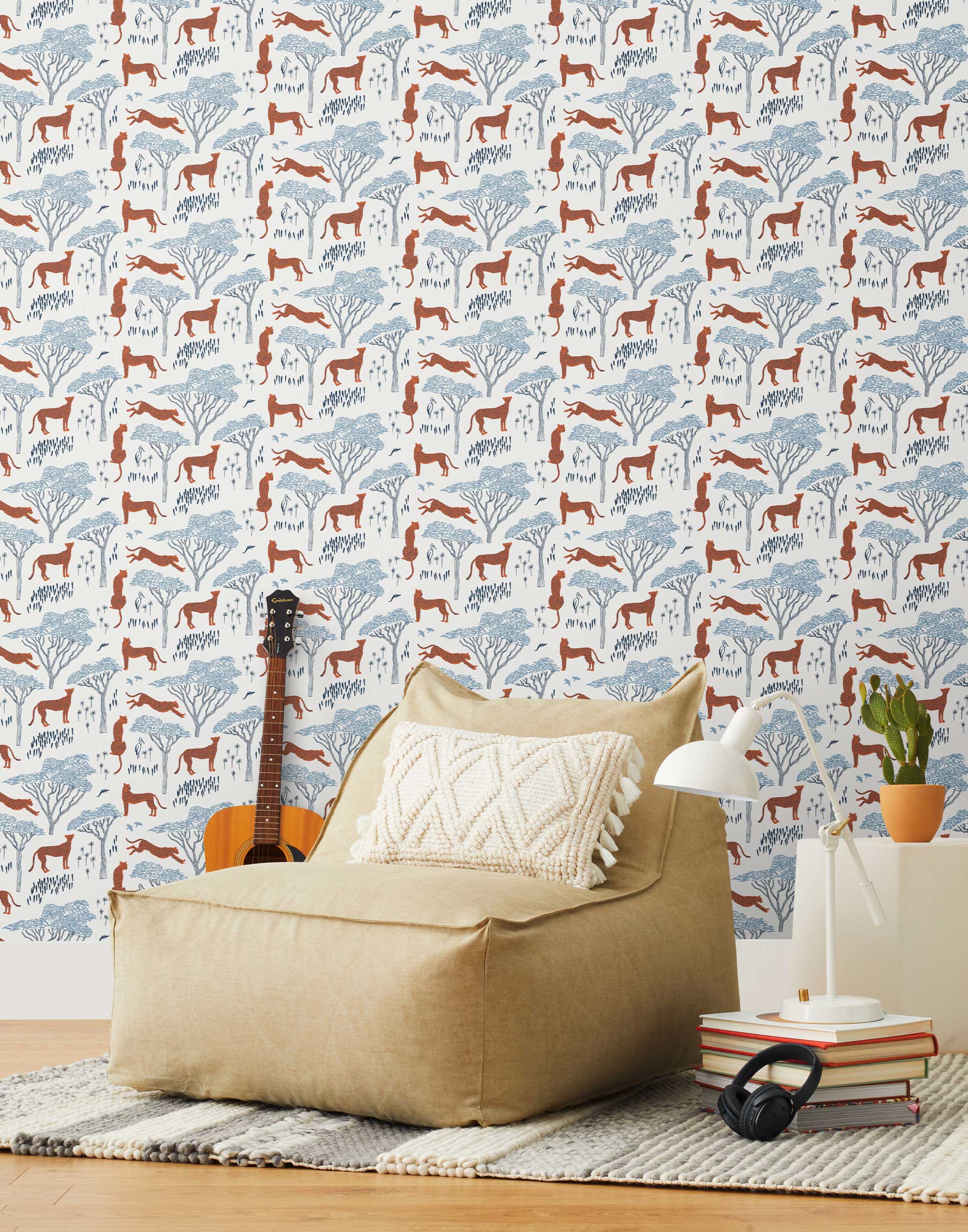 Our Serengeti wallpaper features orange cheetahs and navy birds scattered among blue acacia trees on a white background, reflecting the powerful beauty of the vast plains. Designed by Julia Rothman and made in the USA.
