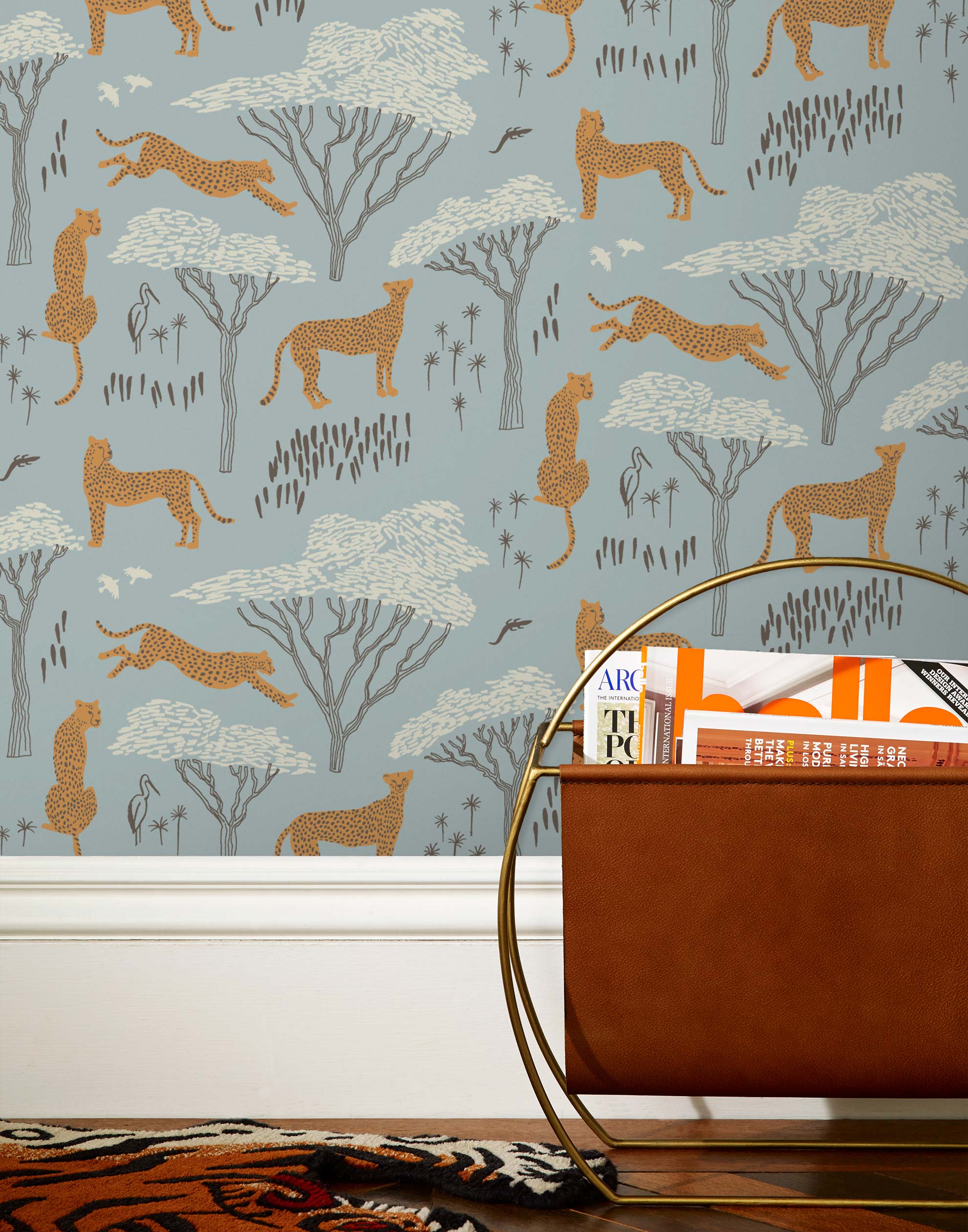 Our Serengeti wallpaper features brown cheetahs and birds scattered among white acacia trees on a dusty blue background, reflecting the powerful beauty of the vast plains. Designed by Julia Rothman and made in the USA.