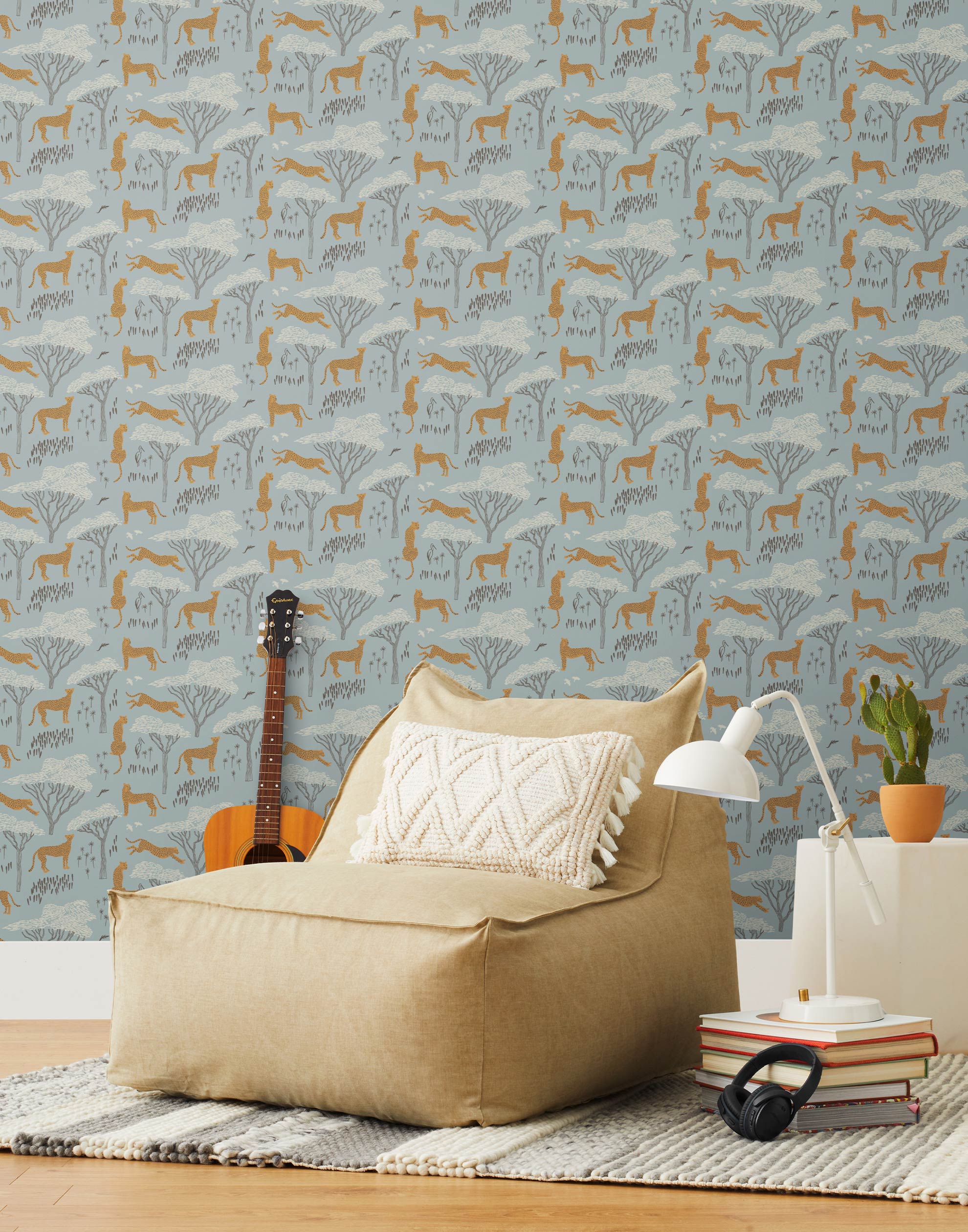 Our Serengeti wallpaper features brown cheetahs and birds scattered among white acacia trees on a dusty blue background, reflecting the powerful beauty of the vast plains. Designed by Julia Rothman and made in the USA.