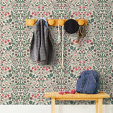 Nora (Blush) wallpaper features a garden of bees, birds, strawberries, and flowers in green, blue and red on a pink background.