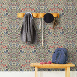 Nora (Taupe) wallpaper features a garden of bees, birds, strawberries, and flowers in shades of blue, pink, and white on a cream background.