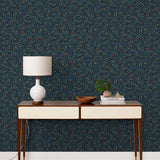 Olive Grove (Ebony) featuring a leafy vine motif in shades of green and blue with deep red accents on a black background | Schoolhouse x Hygge & West Wallpaper Collection