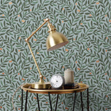 Olive Grove (Mist) featuring a leafy vine motif in shades of green with copper accents on dusty blue background | Schoolhouse x Hygge & West Wallpaper Collection