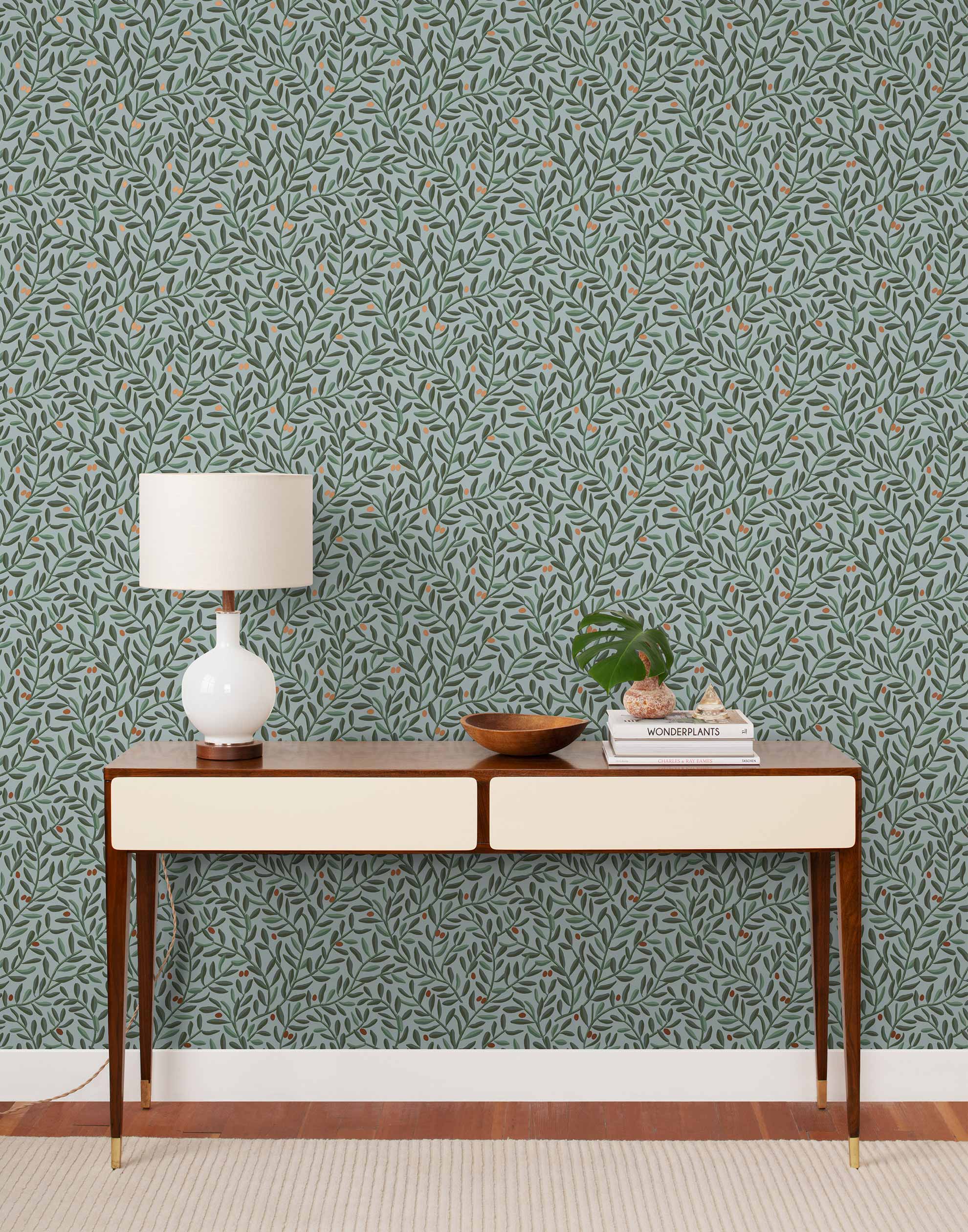 Olive Grove (Mist) featuring a leafy vine motif in shades of green with copper accents on dusty blue background | Schoolhouse x Hygge & West Wallpaper Collection
