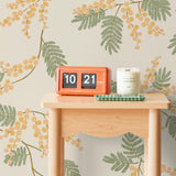 Wallpaper with coral and pink acacia flowers and green leaves on a cream background | Schoolhouse + Hygge & West