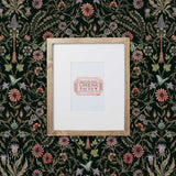 Inspired by the painted ceiling of Glinda and Elphaba's Shiz University dorm room in the movie Wicked, this wallpaper features colorful flowers and a witch's hat and broom on a dark green background.