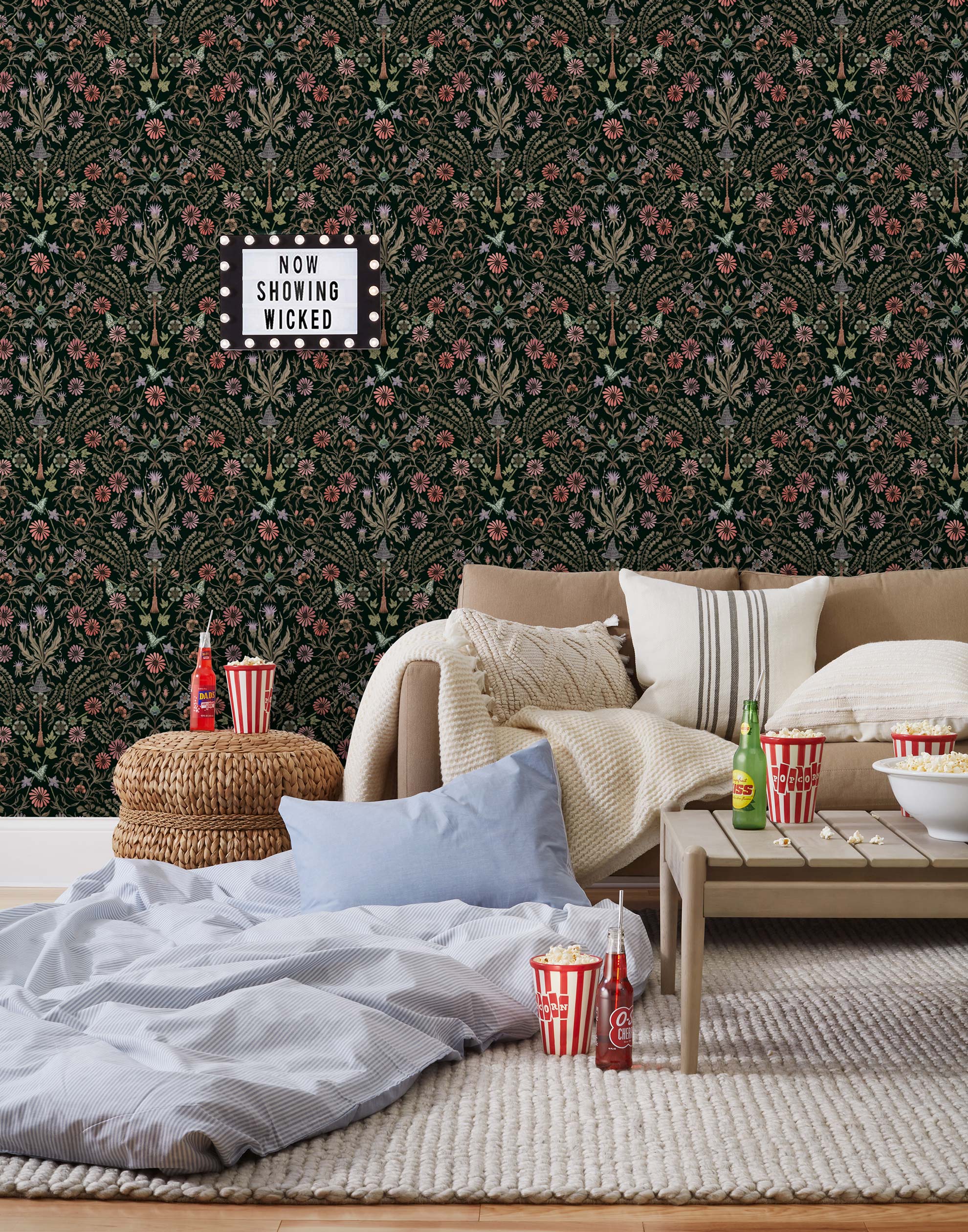 Inspired by the painted ceiling of Glinda and Elphaba's Shiz University dorm room in the movie Wicked, this wallpaper features colorful flowers and a witch's hat and broom on a dark green background.