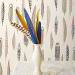 Plumes Natural Wallpaper features delicate feathers in orange, rust, blues and browns on a cream background