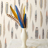 Plumes Natural Wallpaper features delicate feathers in orange, rust, blues and browns on a cream background