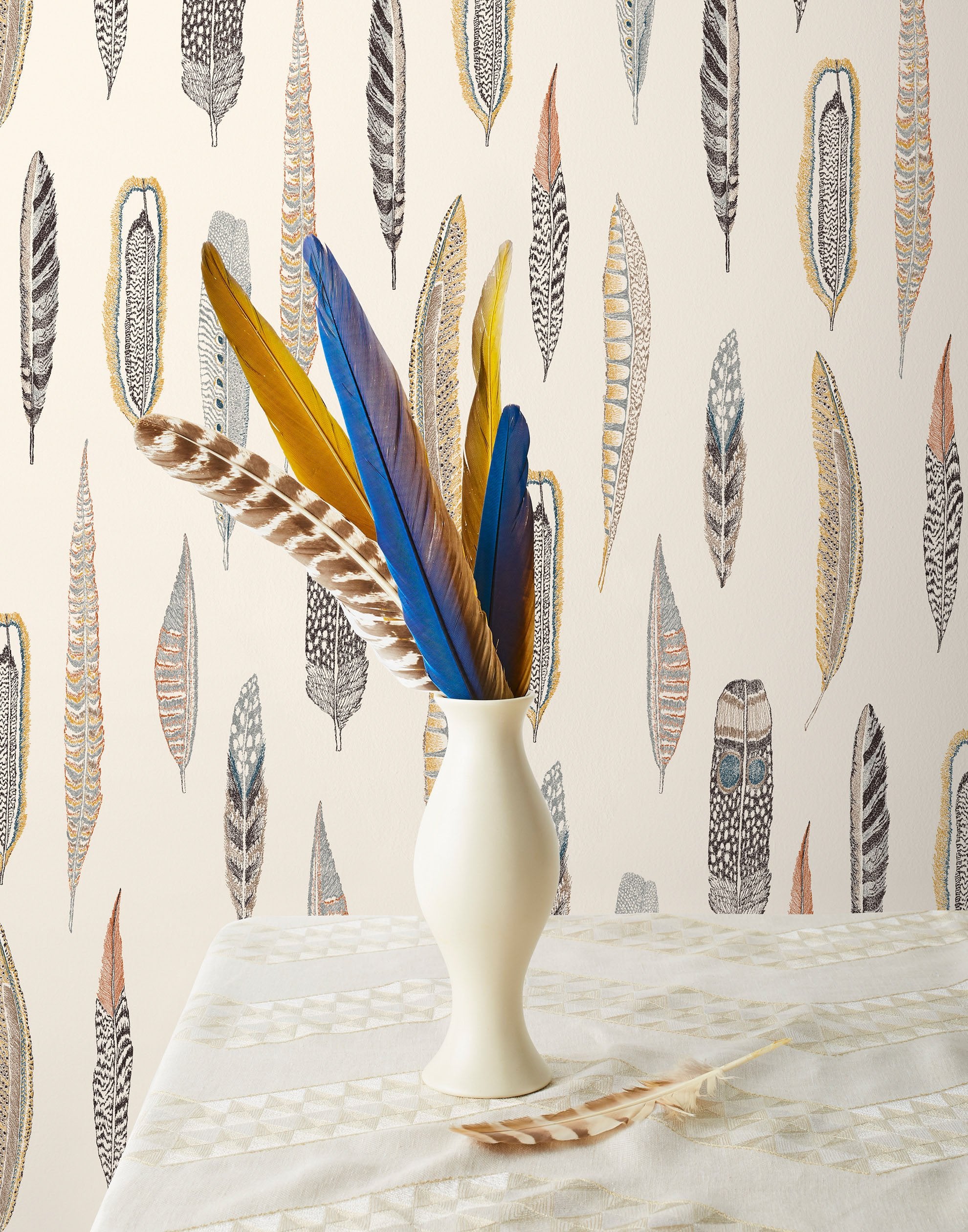 Plumes Natural Wallpaper features delicate feathers in orange, rust, blues and browns on a cream background