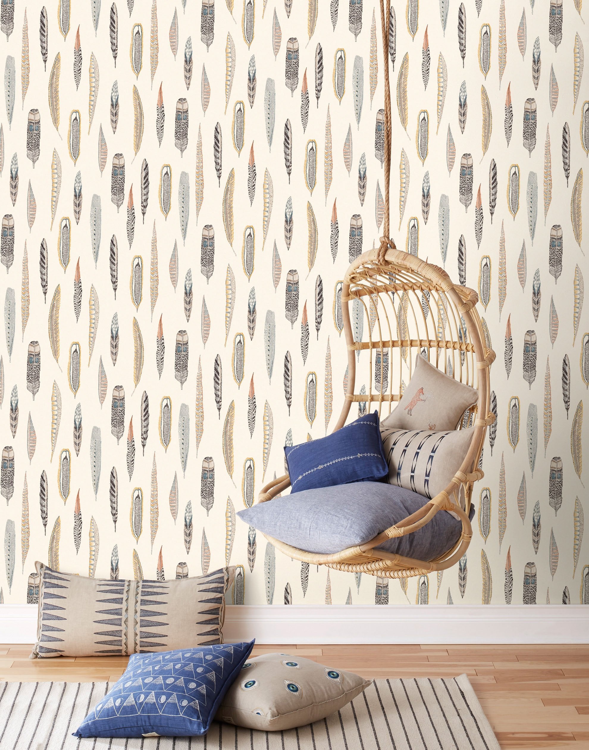 Plumes Natural Wallpaper features delicate feathers in orange, rust, blues and browns on a cream background