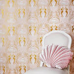 Mermaids (Shell Pink) wallpaper | Mermaids, fish, octopi and ships float in this charming design | Gold and white artwork on a pink ground