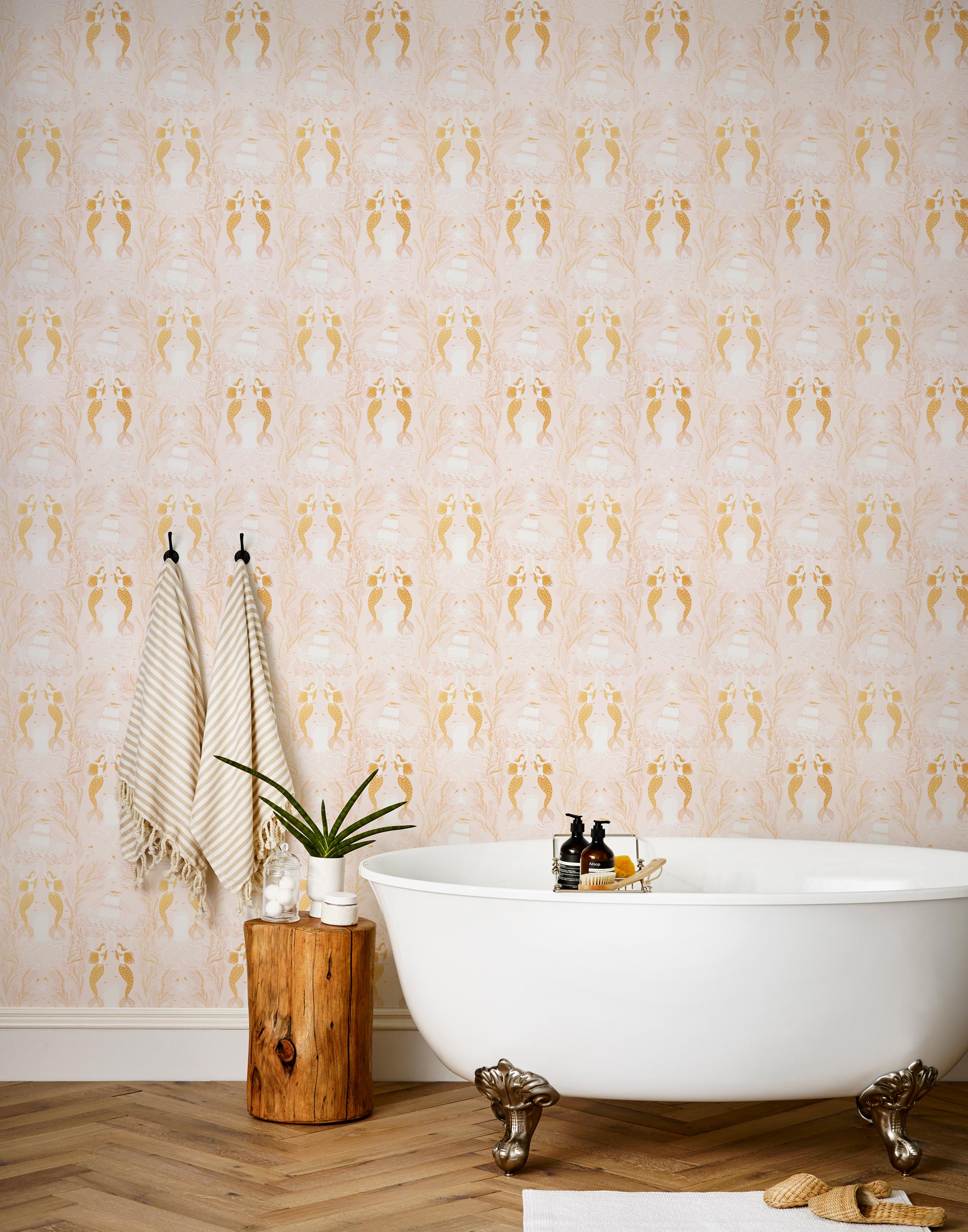 Mermaids (Shell Pink) wallpaper | Mermaids, fish, octopi and ships float in this charming design | Gold and white artwork on a pink ground