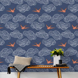 Daydream (Indigo) wallpaper features a pattern of flying birds and floating clouds in orange white and blue