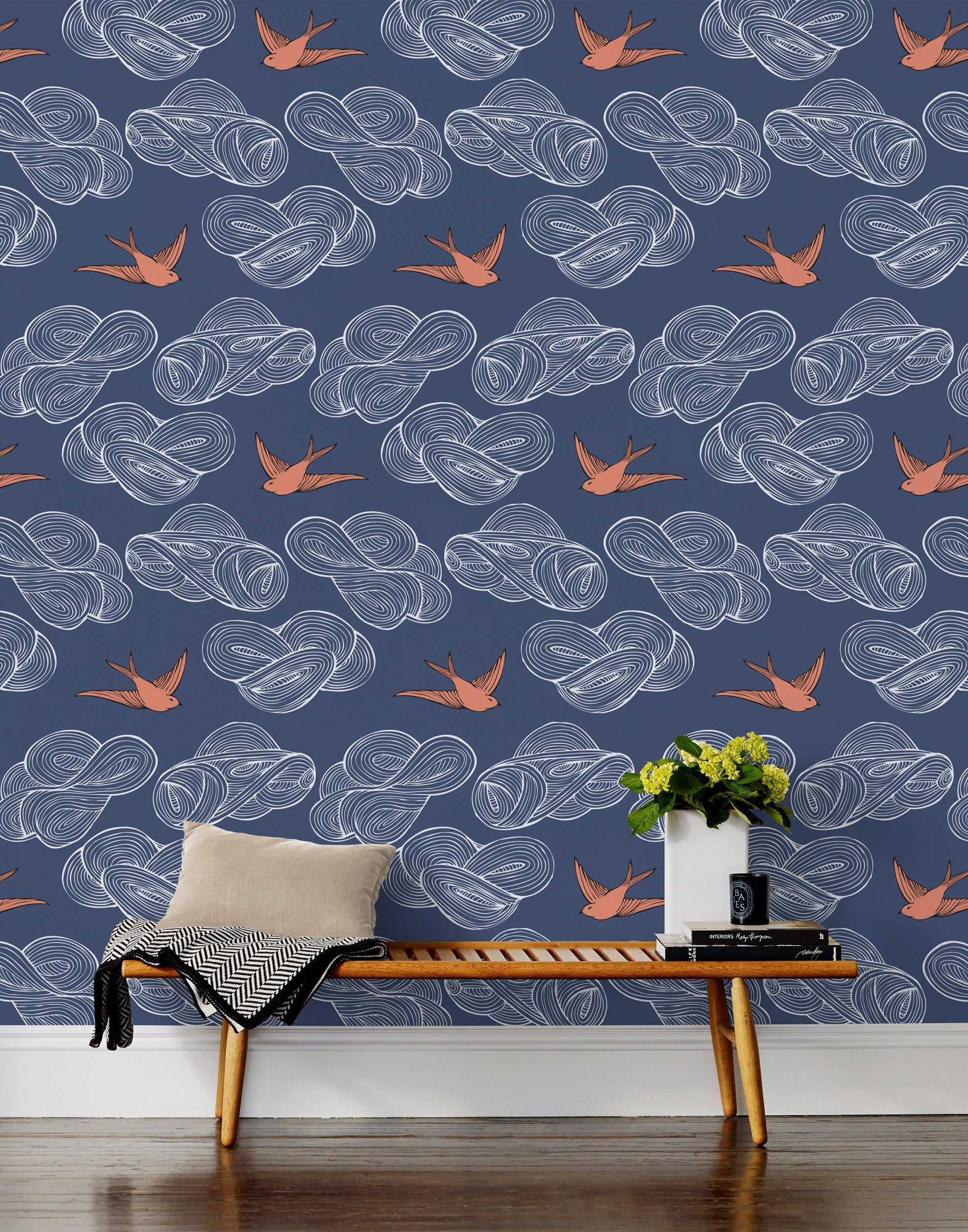 Daydream (Indigo) wallpaper features a pattern of flying birds and floating clouds in orange white and blue