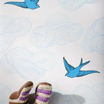Daydream (French Blue) features a pattern of flying birds and floating clouds in shades of blue on white