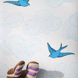 Daydream (French Blue) features a pattern of flying birds and floating clouds in shades of blue on white