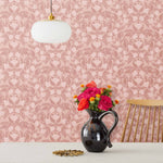 Symmetry wallpaper is a stylized floral wallpaper and designed in linocut style by Katharine Watson for Hygge & West | Dark pink and light pink flowers on a rose pink wallpaper background.
