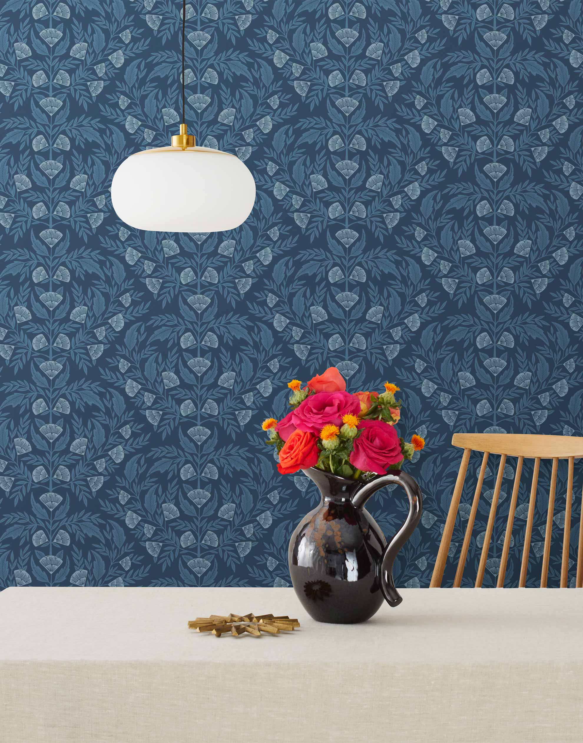 Symmetry wallpaper is a stylized floral wallpaper and designed in linocut style by Katharine Watson for Hygge & West | Light blue flowers on a navy blue wallpaper background.