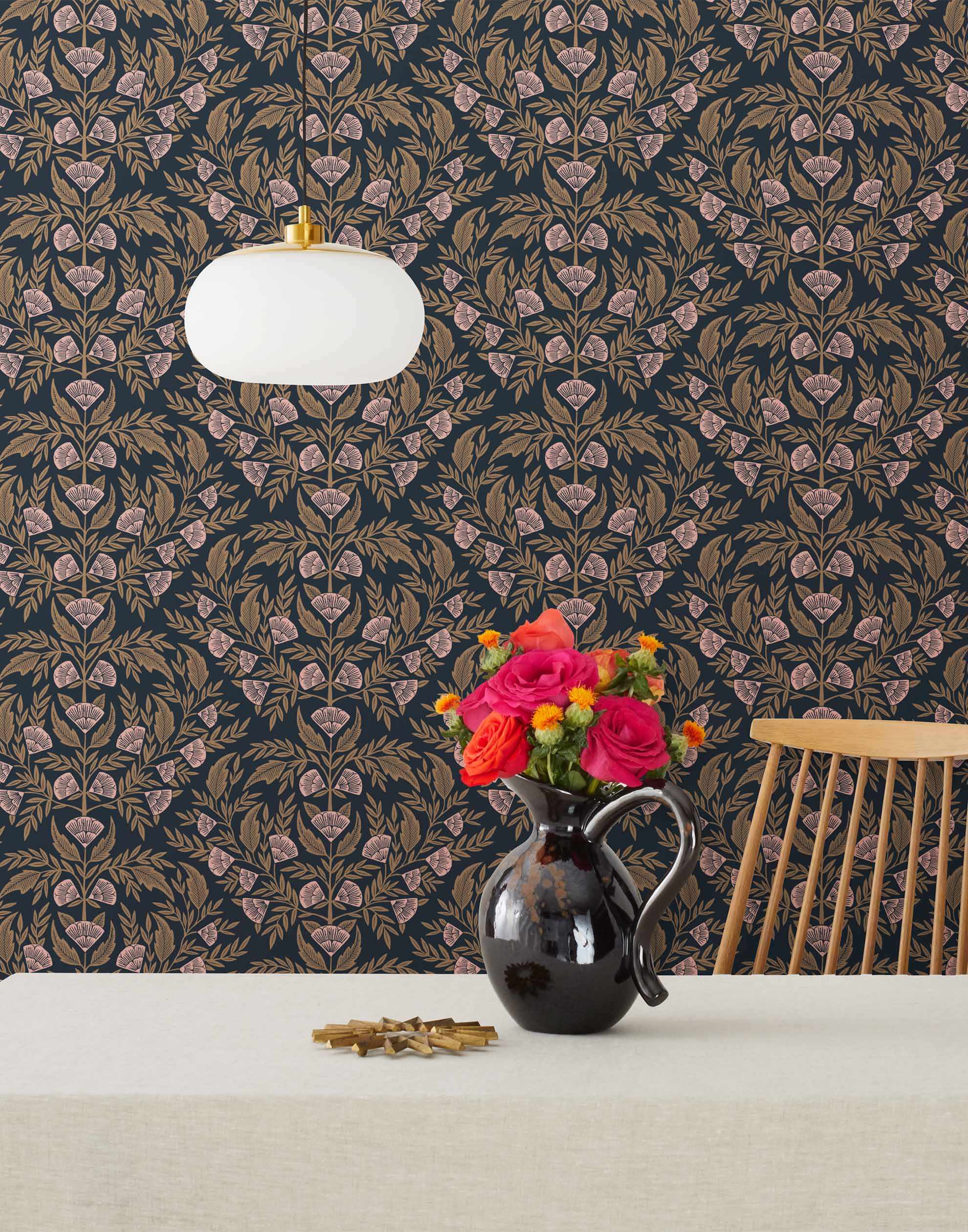 Symmetry wallpaper is a stylized floral wallpaper and designed in linocut style by Katharine Watson for Hygge & West | Metallic gold and pink flowers on a soft black wallpaper background.