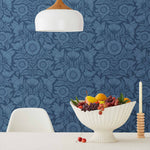 Conservatory wallpaper featuring stylized petals and leaves dervived from a block-print technique was designed by Katharine Watson for Hygge & West. Featuring cornflower blue flowers on a navy blue wallpaper background.