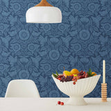 Conservatory wallpaper featuring stylized petals and leaves dervived from a block-print technique was designed by Katharine Watson for Hygge & West. Featuring cornflower blue flowers on a navy blue wallpaper background.