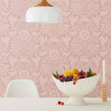 Conservatory wallpaper featuring stylized petals and leaves dervived from a block-print technique was designed by Katharine Watson for Hygge & West. Featuring light pink flowers on a rose pink wallpaper background.