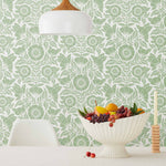 Conservatory wallpaper featuring stylized petals and leaves dervived from a block-print technique was designed by Katharine Watson for Hygge & West. Featuring sage green flowers on a white wallpaper background.