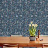 Sonoma (Indigo) wallpaper with green, mauve, coral and pink flowers and leaves on a blue background