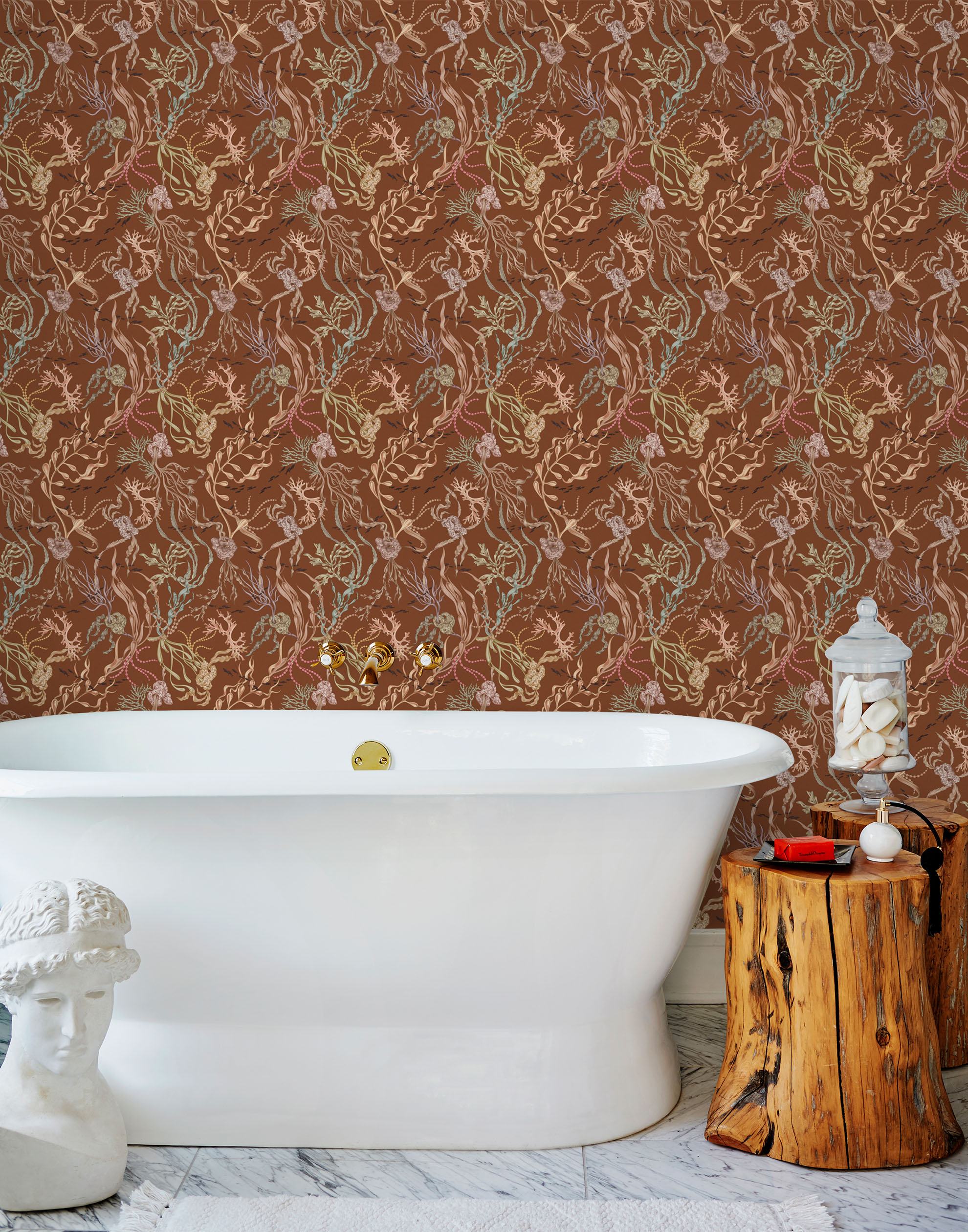Atoll (Sienna) wallpaper features shades of green, pink, peach, taupe and black seaweed and coral on a brown background