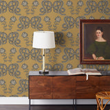 Serpentine (Butterscotch) Wallpaper featuring charcoal and cream snakes and flowers on a golden ochre yellow background