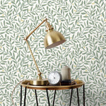 Olive Grove (Spruce) featuring a leafy vine motif in shades of green with pale yellow accents on an off white background | Schoolhouse x Hygge & West Wallpaper Collection