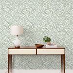 Olive Grove (Spruce) featuring a leafy vine motif in shades of green with pale yellow accents on an off white background | Schoolhouse x Hygge & West Wallpaper Collection