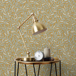 Olive Grove (Ochre) featuring a leafy vine motif in shades light green with metallic silver accents on a mustard yellow background | Schoolhouse x Hygge & West Wallpaper Collection