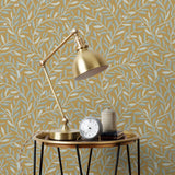 Olive Grove (Ochre) featuring a leafy vine motif in shades light green with metallic silver accents on a mustard yellow background | Schoolhouse x Hygge & West Wallpaper Collection
