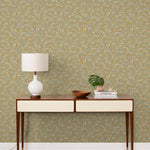 Olive Grove (Ochre) featuring a leafy vine motif in shades light green with metallic silver accents on a mustard yellow background | Schoolhouse x Hygge & West Wallpaper Collection