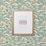 Amity Sunset (Sky) Wallpaper with dusty blue, cream and orange illustrations depicts scenes from the iconic movie Jaws and was created in collaboration with Universal | Hygge & West